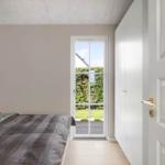 Schlafzimmer mit Bett, weißen Schränken und Tür zum Garten.