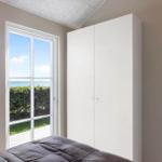 Schlafzimmer mit Blick auf Meer, weißer Schrank und Tür.
