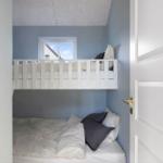 Ein Schlafzimmer mit einem hohen Bett und einem unteren Bett. Die Wände sind blau gestrichen.
