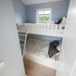 Zimmer mit Doppelstockbett, Fenster und Holzboden.