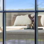 Durch Fenster sichtbarer Sitzbereich mit Sofa und Tisch mit Tassen.