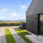 Haus mit Holzfassade und Eingangstür. Blick auf das Meer und einen Weg durch Gras.