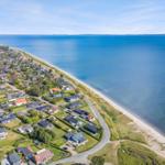 Aeriale Aufnahme einer Küstenstadt mit Häusern, Strand und blauem Meer.