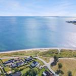 Aerofoto einer Küstenlandschaft mit Strand, Häusern und Meer.