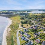 Aerielansicht einer Küstenlandschaft mit Häusern, Strand und Wasser.