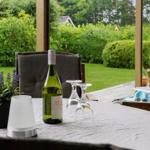 Tisch mit Weinglas, Flasche und Pflanze im Freien mit Blick auf Garten.