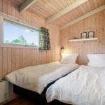 Zwei Einzelbetten in einem Holzhauszimmer mit Fenster und Wandregal.