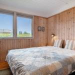 Schlafzimmer mit Holzwand und großem Fenster mit Blick auf die Landschaft.