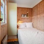 Schlafzimmer mit Holzwand, Bett, Fenster und Schrank.