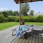 Terrasse mit Liegestühlen, Grill und Blick auf grünen Garten.