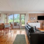 Wohn- und Essbereich mit Holzdecke, Sofa und Blick auf den Garten.