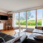 Wohnzimmer mit großem Fenster, Ledersofa und Holzwand