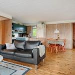 Wohn- und Essbereich mit Holzwand, Sofa, Tisch und Stühlen.