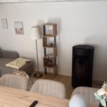 Wohnzimmer mit Sofa, TV und Stehlampe. Holztisch mit Stühlen und Blumen.