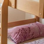 Ein Etagenbett mit Holzgestell und rosa Bettwäsche mit Blumenmuster.