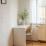 Schreibtisch mit Lampe und Pflanze neben Fenster mit Vorhang