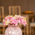 Ein Vasenarrangement mit rosa und gelben Hortensien auf einem Tisch.