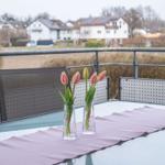 Terrasse mit Tisch, Stühlen und Tulpenblumen. Blick auf Wohnhäuser und Grünflächen.