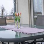 Glas-Tisch mit rosa Tischdecke und Tulpen in Vasen auf Balkon