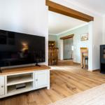 Wohnzimmer mit Fernseher, Holzofen und angrenzendem Essbereich.