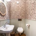 Badezimmer mit Waschbecken, Toilette und Spiegel mit Korbrahmen.