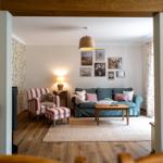 Wohnzimmer mit Sofa, Sessel, Tisch und Wandbildern.