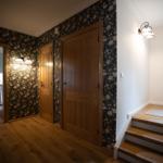 Flur mit Holzboden, floraler Tapete und Treppe zur oberen Etage.