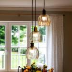 Drei hängende Lampen mit Glasgehäusen über einem Tisch mit Blumen