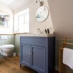 Badezimmer mit blauem Waschbeckenunterschrank, Spiegel und Toilette.