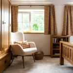 Schlafzimmer mit Holzbett, Kleiderschrank und Sessel vor Fenstern mit karierten Vorhängen.