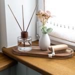 Holztablett mit Duftdiffusor, Vase und Bürste auf Fensterbank.