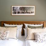 Schlafzimmer mit Holzbett, Kissen und Bild an der Wand.