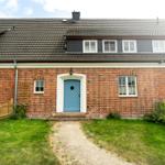 Ein Haus mit Backsteinfassade, blauer Haustür und grünem Gartenweg.