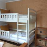 Zimmer mit Doppelstockbett, Holzkommode und gemustertem Wandbezug.