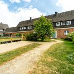 Roter Backsteinbau mit Gartentor und gepflastertem Weg.