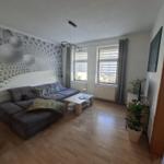 Living room with sofa, table, and windows. Wall with geometric pattern.