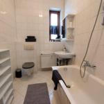 Bathroom with bathtub, sink, toilet, and window.