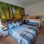 Room with double bed, bunk bed, and forest mural on the wall.