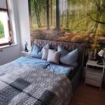 Bedroom with bed, nightstands, and forest wall mural.
