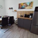 Kitchen with refrigerator, microwave, and dining area with table and chairs.
