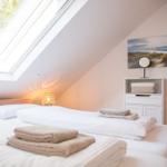 Schlafzimmer mit Dachfenster, Bett, Nachttisch und Wandbild.