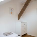 Schlafzimmer mit Bett, Kleiderschrank und Holzbalken an der Decke.