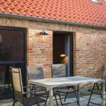 Terrasse mit Tisch und Stühlen vor Backsteinhaus mit rotem Dach