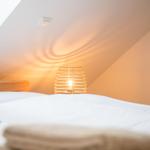 Schlafzimmer mit Dachschrägen, Bett, Lampe und Dachfenster.