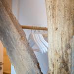 Kleiderständer mit weißen Haken zwischen rustikalen Holzelementen.