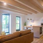 Wohnküche mit Holzbalkendecke, Sofa, TV und Terrasse. Moderne Einrichtung.