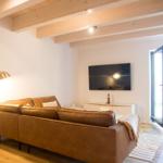 Wohnzimmer mit braunem Sofa, Fernseher und Terrassentür.