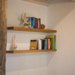 Zwei Holzregale an der Wand mit Büchern und Meeresdekoration.