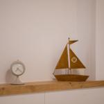 Ein goldfarbenes Segelschiffmodell und eine Uhr stehen auf einer Holzoberfläche.