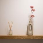 Holzregal mit Duftflasche und Vasenblumen